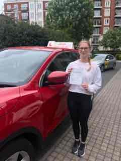 Successful driving student holding certificate next to the AG Driving School car.