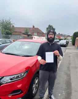 Successful driving student holding pass certificate in front of the AG Driving School car.